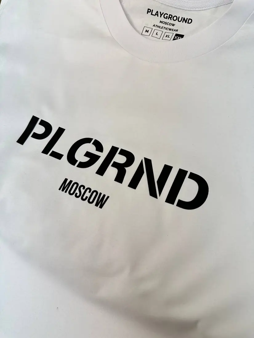 Белая футболка с чёрным принтом PLGRND MOSCOW и брендированной биркой на горловине